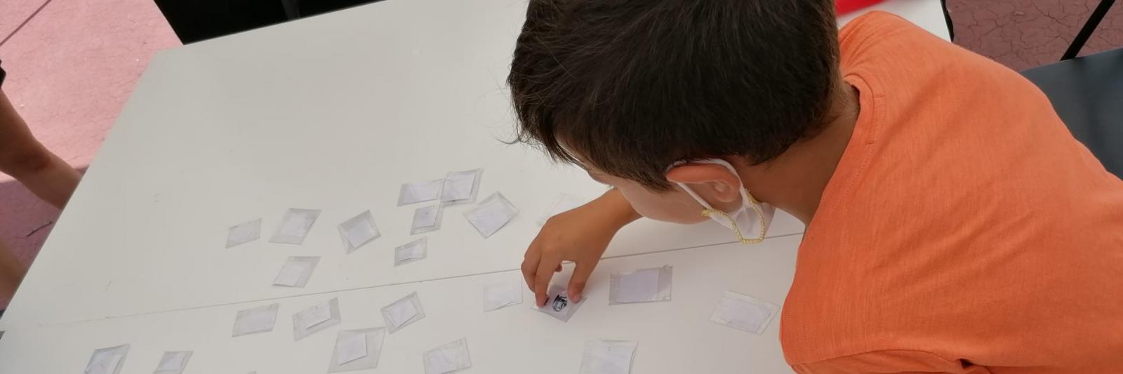 Un bambino gira le carte del memory appoggiate su un tavolo.