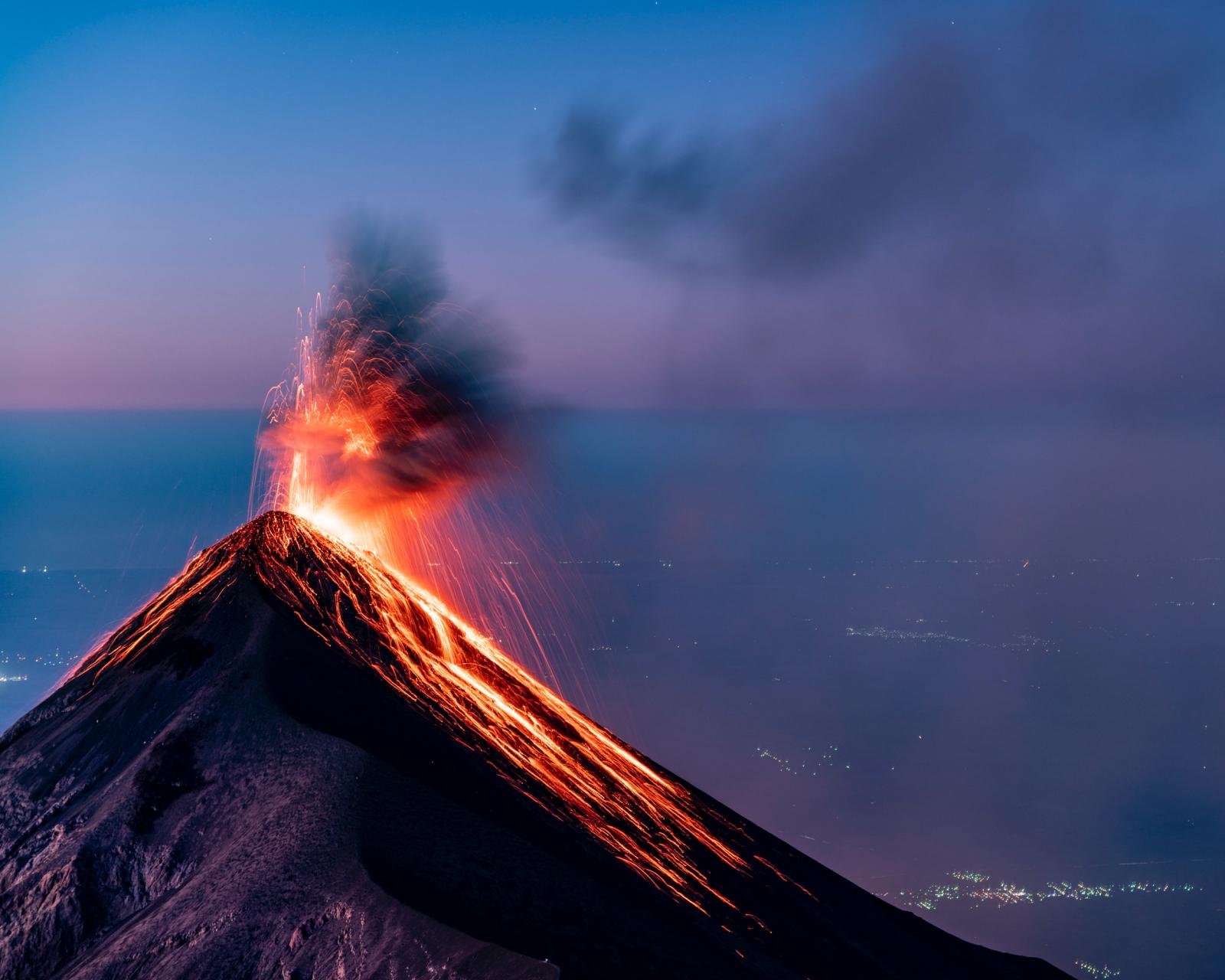 Vulcano che sta eruttando, sullo sfondo si vede il mare.