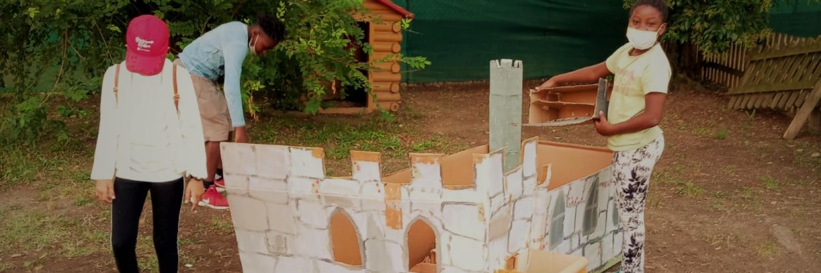 Bambini che giocano con un castello di cartone.