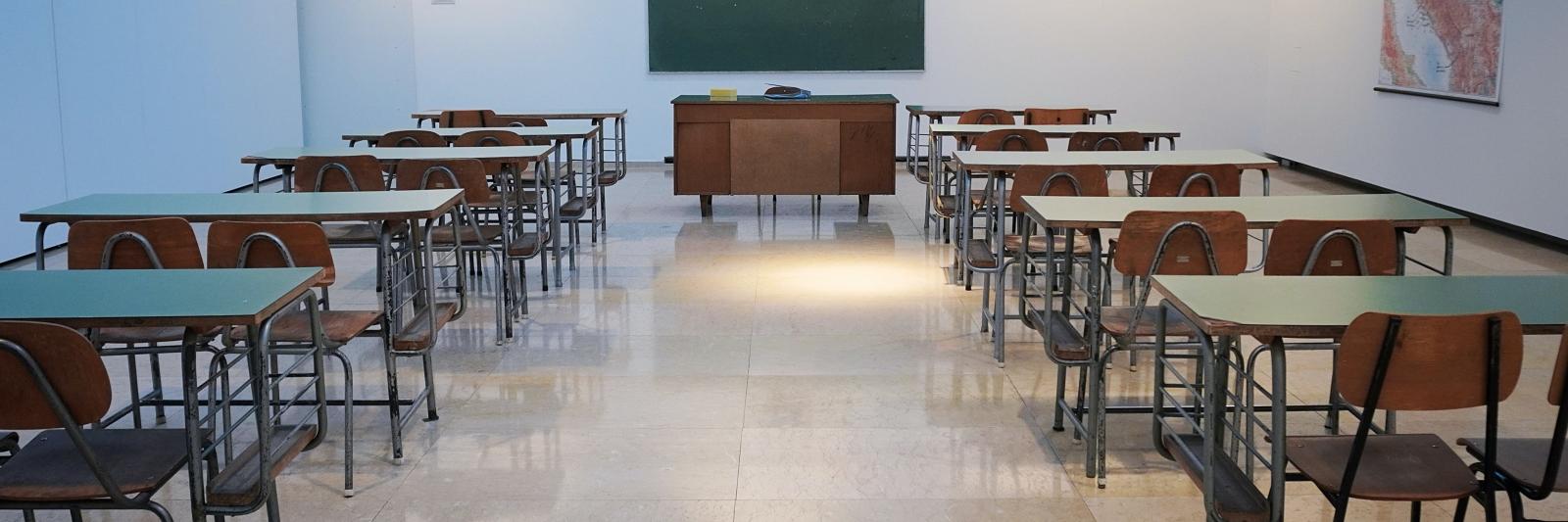 aula scolastica con banchi e cattedra vuoti