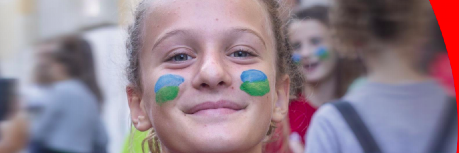 Bambina sorridente con il viso pitturato con i colori del mondo