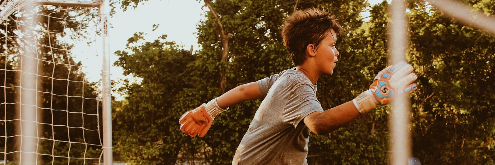 bambino che gioca a calcio facendo il portiere