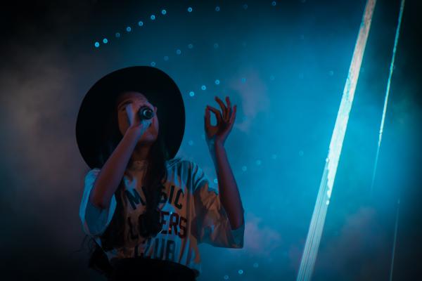 Ragazza che canta con un microfono, con luci del palco