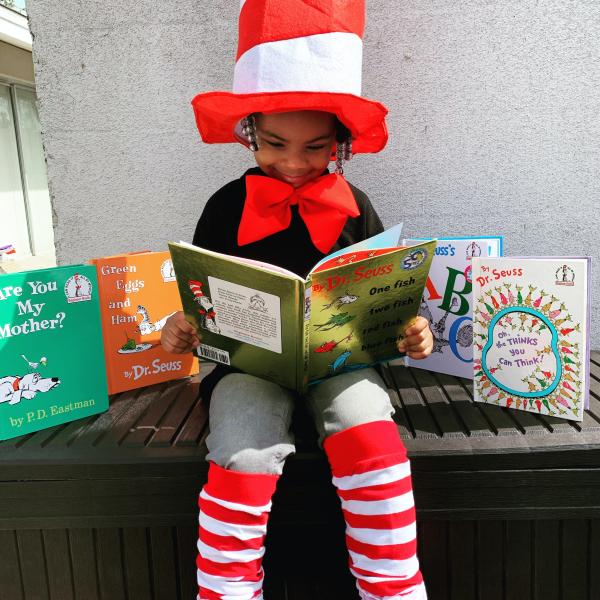 Bambina che legge un libro con un travestimento da Dr. Seuss