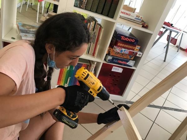 Una ragazza che sta usando il trapano per montare una porta da calcio in legno