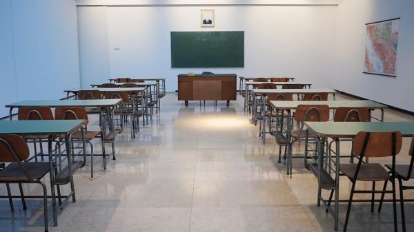 aula scolastica con banchi e cattedra vuoti