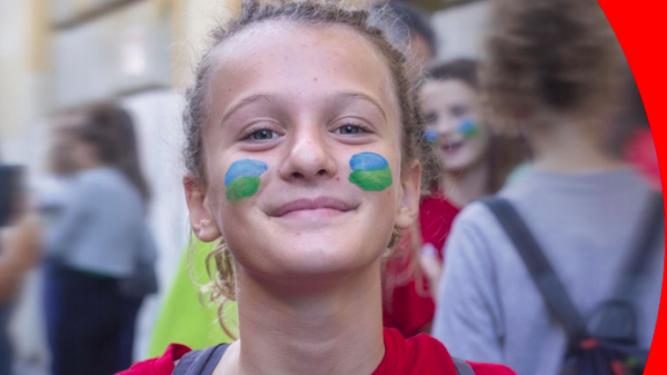 Bambina sorridente con il viso pitturato con i colori del mondo