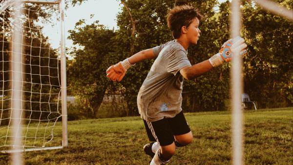 bambino che gioca a calcio facendo il portiere