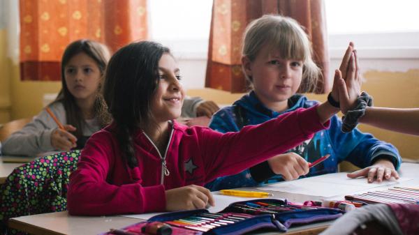 Bambine in una classe che si danno il 5